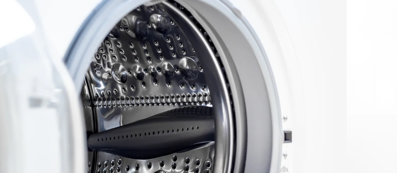 Open door of a front-loading washing machine showing the drum and the rubber door gasket